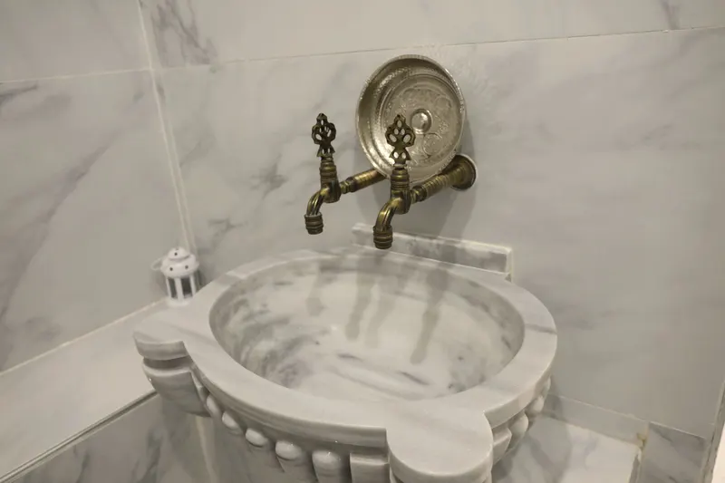 Le hammam : vasque de marbre sculpté et robinets en laiton