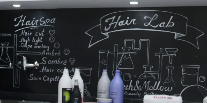 Le tableau noir du Hair Lab : « Hair Spa » (hair cut, high light, coupe brushing, ambré, sombré, hair color, soin capillaire) et fioles dessinées à la craie