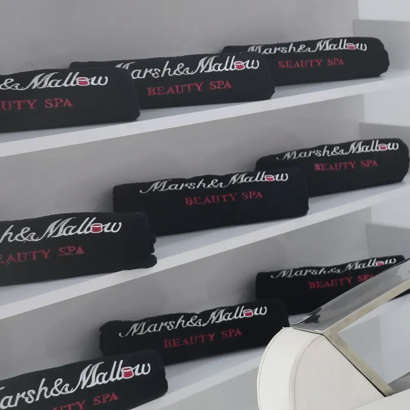 Serviettes noires brodées « Marsh&Mallow Beauty Spa » rangées sur les étagères du Hair Lab