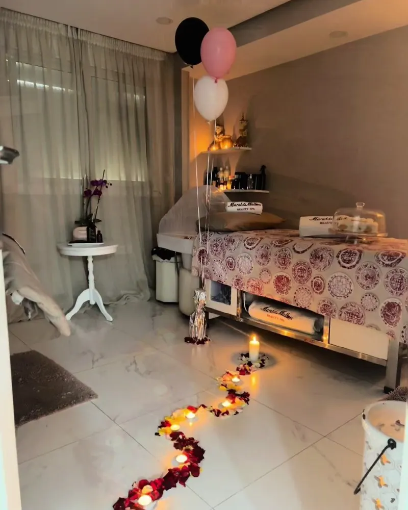 Surprise d’anniversaire préparée dans une cabine : ballons noirs, roses et blancs, bougies et chemin de pétales